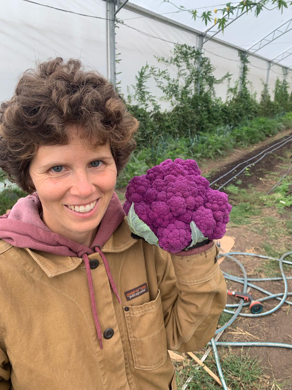 Agustina Olivera en el invernáculo sosteniendo un brócoli morado recién cosechado